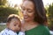 Happy African American  middle aged grandmother holding her three month old grandson in the garden, close up, head and shoulders