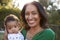 Happy African American  middle aged grandmother holding her three month old grandson in the garden and smiling to camera, close up