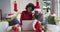 Happy african american mother and adult daughter in santa hats on christmas video call, slow motion