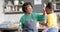 Happy african american mother and daughter frying pancakes and high fiving in kitchen, slow motion