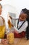 Happy african american mother and daughter pouring pasta to glass jar in kitchen at home, copy space