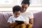 Happy african american mother sitting with son on couch.