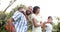 Happy african american parents, daughter and son piggybacking and walking in garden, slow motion