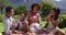 Happy african american parents, daughter and son sitting outdoors on blanket, eating fruits