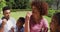 Happy african american parents, daughter and son sitting outdoors on blanket, eating fruits