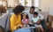 Happy African American parents with their cute children reading storybook on the sofa