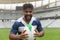 Happy African American Rugby player standing with rugby ball in stadium