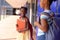 Happy african american schoolchildren standing next to locker at school