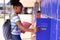 Happy african american schoolgirl standing next to locker at school