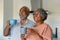 Happy african american senior couple holding mugs with coffee and talking