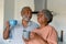 Happy african american senior couple holding mugs with coffee and talking