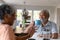 Happy african american senior couple sitting in kitchen with coffee and talking