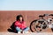 happy african-american woman with bike sitting on street and writing in a notebook