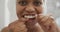 Happy african american woman flossing teeth and using smartphone in bathroom