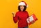 Happy African American woman overjoyed holding christmas gifts and saying YES on orange background, smiles