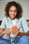 Happy African American woman using phone relaxing on sofa at home.