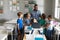 Happy african american young male teacher teaching laptop to multiracial elementary students