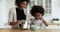 Happy african american young mother teaching daughter making pancakes.