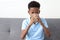 Happy African boy drinking fresh milk from a glass while sitting on the sofa in the living room. children grow up with eating