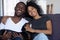 Happy african couple playing with dog sitting on couch, portrait