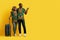 Happy african couple travelers pointing at copy space on yellow
