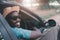 Happy african driver smiling while sitting in a car with open front window