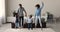 Happy African family with kids holding hands jumping indoors