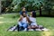 Happy African family of three having picnic in park on summer day. Young family outdoors in a park, sitting on a