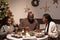 Happy African family of three interacting by served festive table