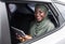 Happy African Islamic Lady Sitting On Backseat In Car With Digital Tablet