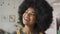 Happy African lady with Afro hair looks at camera stands in cafe, headshot.