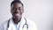 Happy african male doctor wearing white coat standing in medical office.
