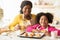Happy African Mom And Little Daughter Enjoying Freshly Baked Croissants In Kitchen