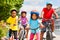 Happy African siblings riding bikes in summer city