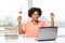 Happy african woman with laptop, books and diploma