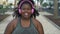 Happy African woman running in the city - Young Afro girl doing jogging session while listening music with headphones