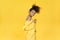 Happy afro girl wear stylish yellow cloth dance isolated on yellow background.