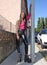 Happy afro-style black girl with long black and blondes braids laughs. She leans on a traffic signpost in a small town