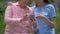 Happy aged woman showing smartphone photos to young volunteer, communication