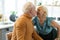 Happy alluring aging spouse tenderly kissing her aged grey-haired husband.