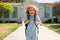 Happy amazed excited kid is going to school. Child boy with bag go to elementary school. Primary school. Pupil go study