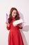 Happy amazed retro styled woman with curly hair in red dress opened present over white background