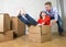 Happy American couple unpacking moving in new house playing with unpacked cardboard boxes