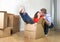 Happy American couple unpacking moving in new house playing with unpacked cardboard boxes