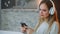 Happy american teen relaxing on sofa at home with smartphone. Young woman streming music on mobile telephone at night