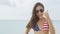 Happy American woman celebrating doing thumbs up with USA flag bikini on beach
