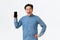 Happy and amused handsome asian guy with braces and glasses react to fantastic news, showing mobile phone screen