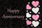 Happy Anniversary greeting with white and pink hearts with candy hearts on black