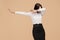 Happy anonymous young modern business woman dance over beige background. Success and winner concept.