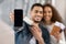 Happy Arab Couple Showing Smartphone With Blank Black Screen In Airport